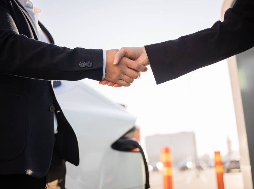 Sprzedawca i klient uściski dłoni przy nowym elektrycznym samochodzie